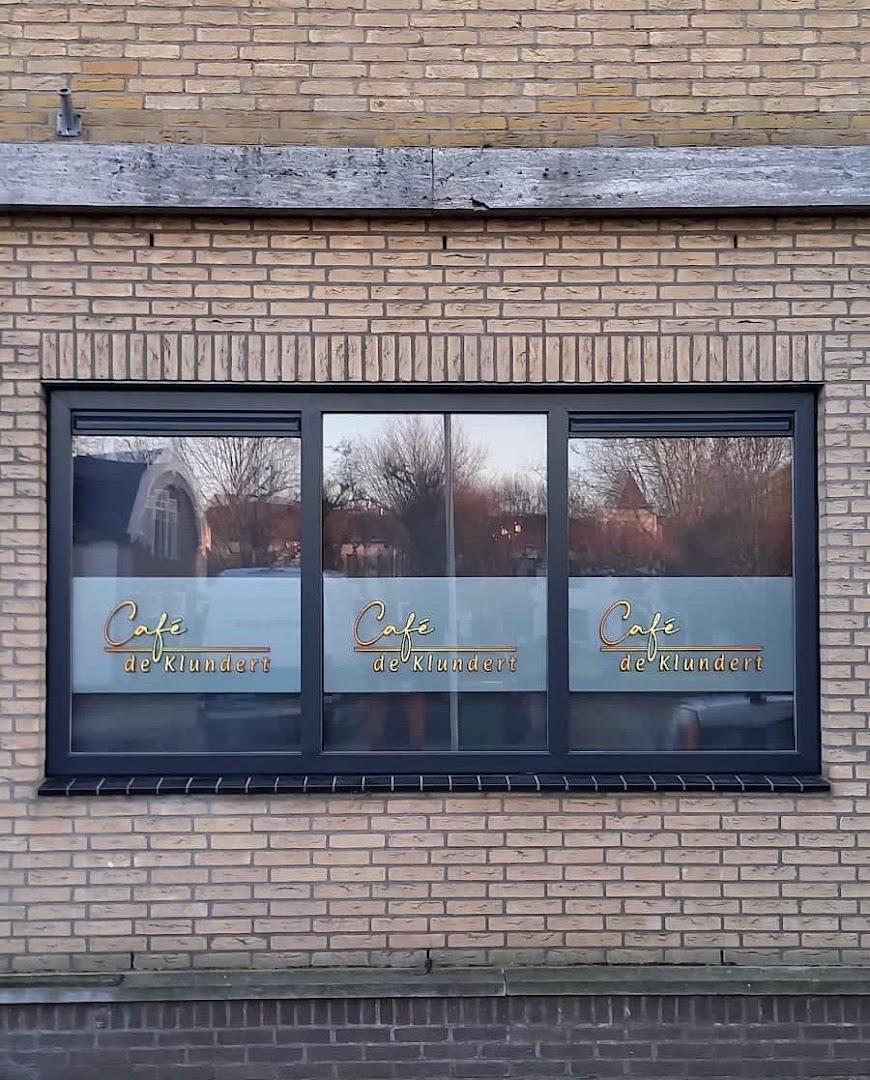 De bar van Café de Klundert, warm verlicht met volle drankenschappen en de Hertog Jan-tap