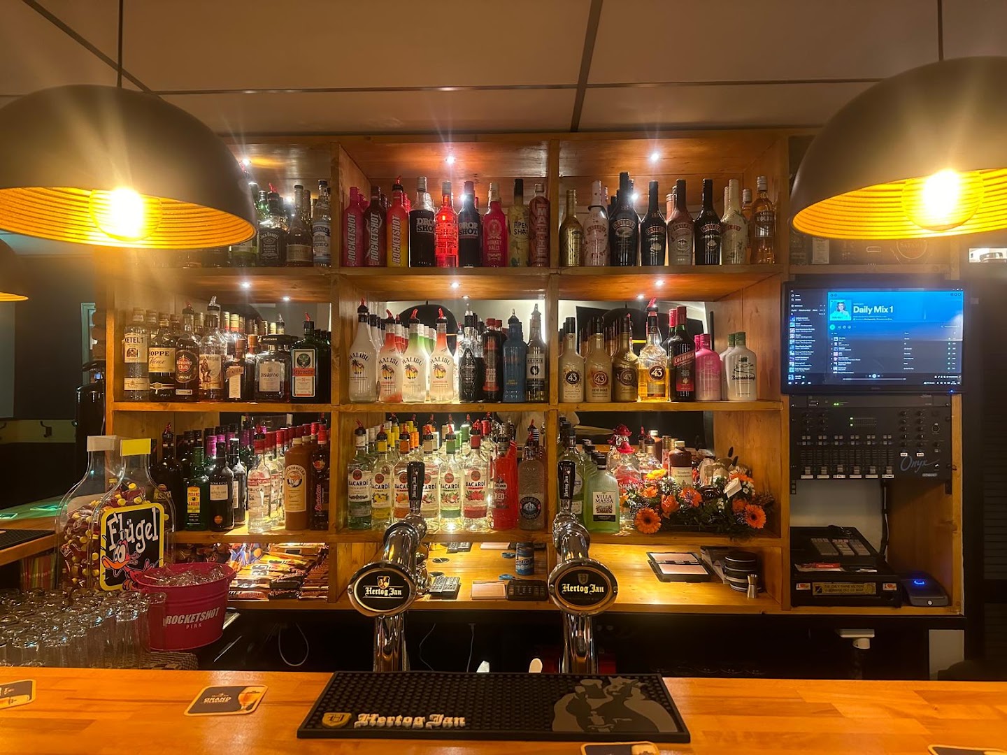 De volle drankenschappen achter de bar van Café de Klundert, warm verlicht